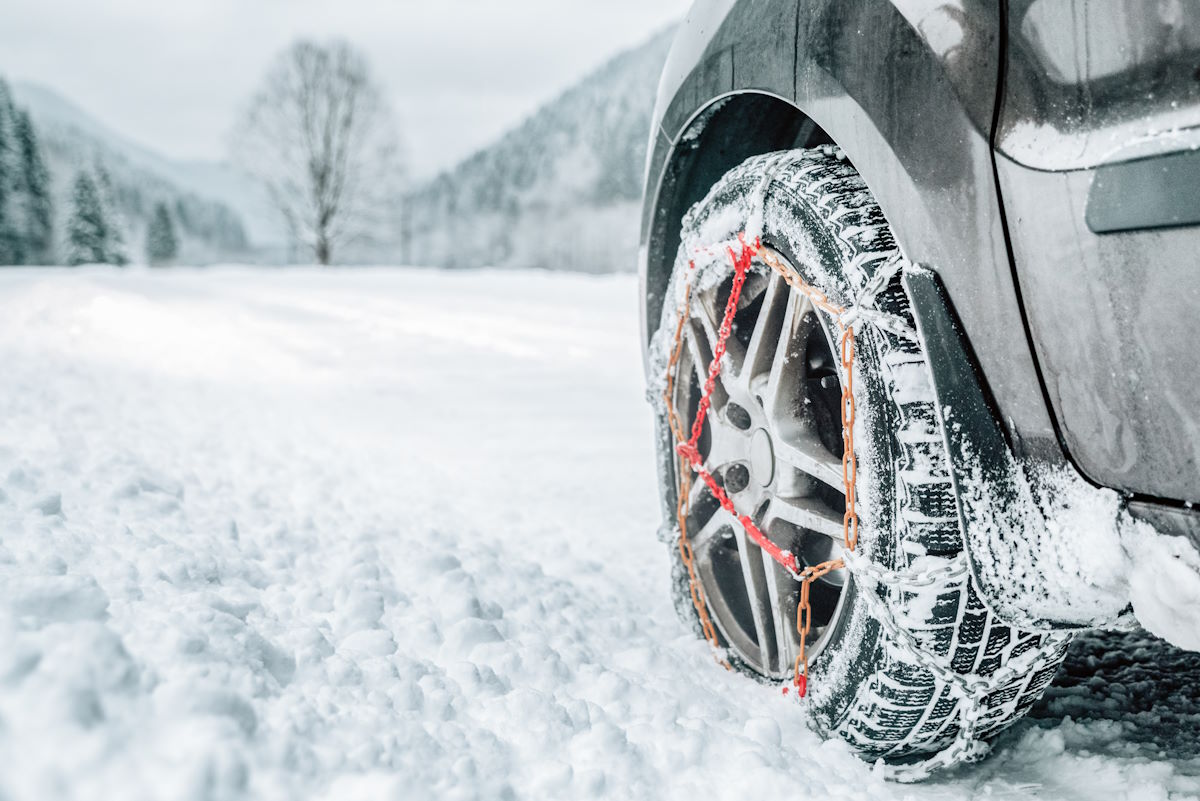 Auto mit montierten Schneeketten in Winterlandschaft Auto mit montierten Schneeketten in Winterlandschaft